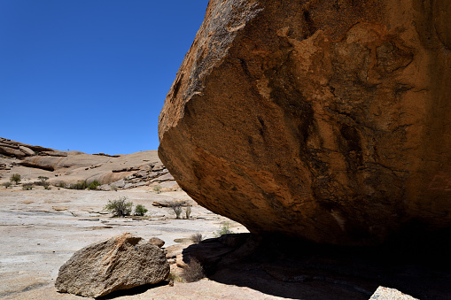 The boulder is the result of millions of years of weathering of granite rock, and is called a ‘woolsack’. The boulder is dominates the photo, only part of it is seen. The sky is blue.\n\nThe area of Bulls Party is reached through the Amieb Guest Farm, near Erongo Mountains in Namibia. It is littered with the results of millions of years of weathering and is geologically interesting because of this. The photo was taken in March 2019.