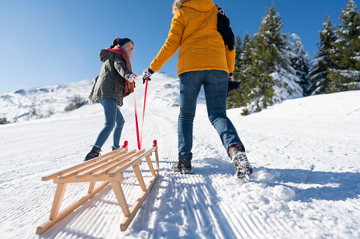 Two girls having fun and going sledding on the snow.