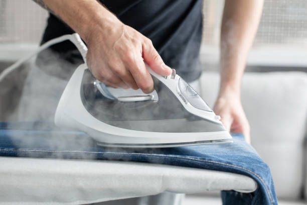 a guy ironing clothes before going outside - contemporary indoors lifestyles domestic room imagens e fotografias de stock