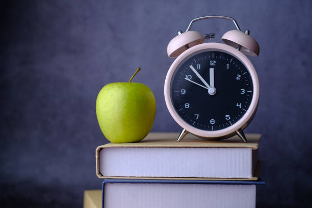 istock clock and apple on stack of books 1202755465