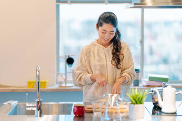 キッチンで朝食を準備する若い女性 - 料理 ストックフォトと画像