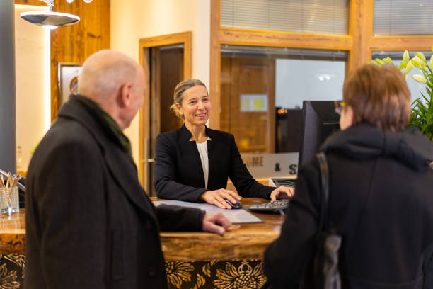 istock friendly receptionist receiving senior couple at hotel reception counter 1202764056