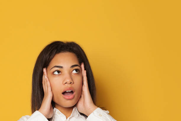 istock Shocked woman looking up on bright yellow background 1202767375