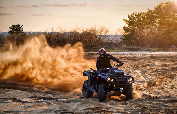 Racing powerful quad bike on the difficult sand in the summer. Racing in the sand on a four-wheel drive quad. motorcycle 4 wheels stock pictures, royalty-free photos & images