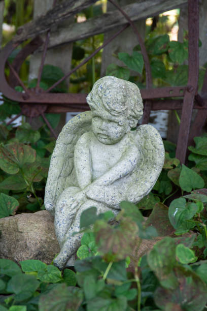 istock Stone angel cupid garden statue surrounded by greenery 1202776122