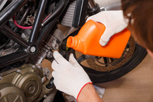 the process of pouring new oil into the motorcycle engine. - coral break imagens e fotografias de stock