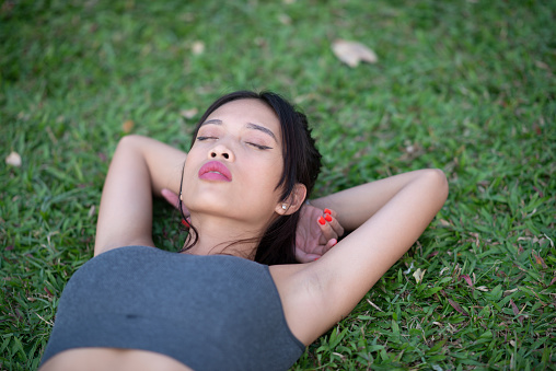 Relax in nature. Beautiful Asian girl relaxing in the park after running.