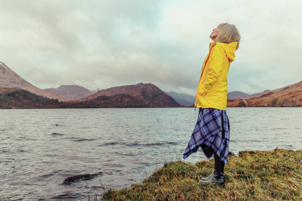 frau inhaliert reine frische luft in den schottischen highlands - highlands region loch reflection mountain stock-fotos und bilder