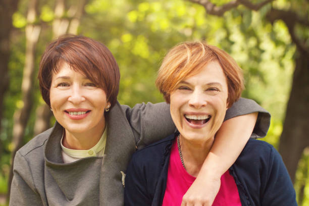 two happy women walking in summer park, portrait - couple walking old middle imagens e fotografias de stock