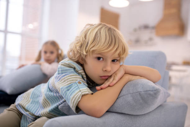 istock Blond cute boy with a pillow in his hands looking unhappy 1202783992