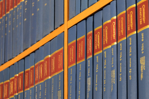A bookcase displaying a line of identical blue, red and gold books