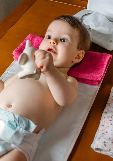 Baby lying playing with a rubber toy Adorable baby lying playing with a rubber toy for children after the change of diaper blow up doll stock pictures, royalty-free photos & images