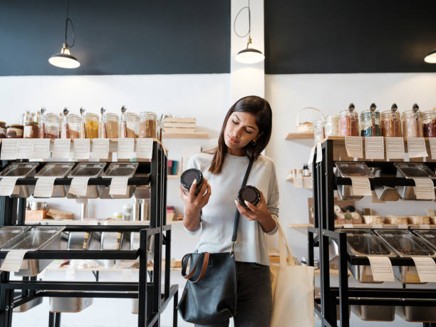 giovane donna che tiene barattoli in un negozio di rifiuti zero - consumerism foto e immagini stock