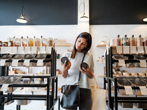 廃棄物ゼロ店で瓶を持つ若い女性 - consumerism ストックフォトと画像