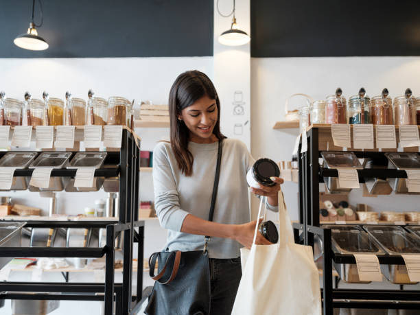 Young woman putting merchandise in reusable shopping bag stock photo