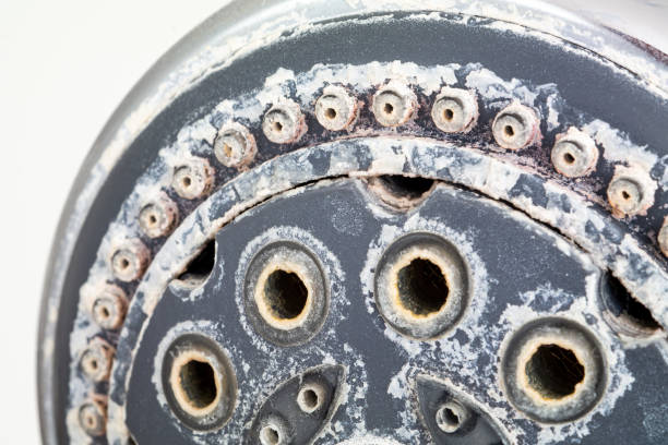 silver round shower head with hard water deposit all around the sprinklers close up macro side shot isolated against white backdrop - toughness imagens e fotografias de stock