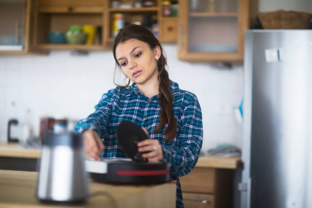 молодая женщина очистки untensil на кухне - kitchen untensil стоковые фото и изображения