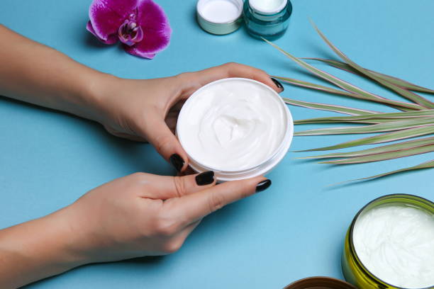istock Woman's hands holding jar with cream over blue table with cosmetic products 1202793746