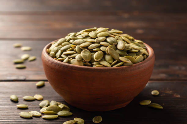 istock Pumpkin seeds in ceramic bowl on dark wooden background 1202794066
