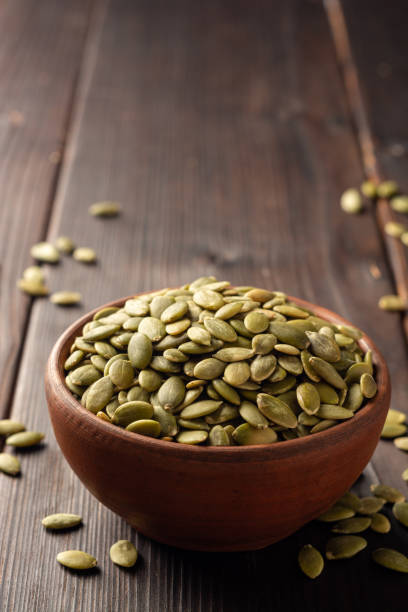 istock Pumpkin seeds in ceramic bowl on dark wooden background 1202794068