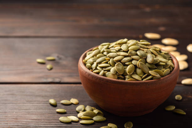 istock Pumpkin seeds in ceramic bowl on dark wooden background 1202794070