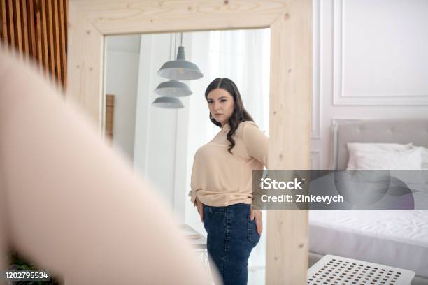 Young Woman In A Beige Blouse Standing And Examining Her Figure Stock Photo - Download Image Now