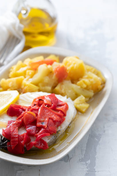istock boiled fish with red pepper, vegetables and olive oil on white dish 1202800703
