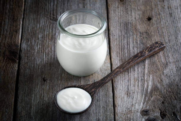 istock Yoghurt pot, wooden table background 1202802505