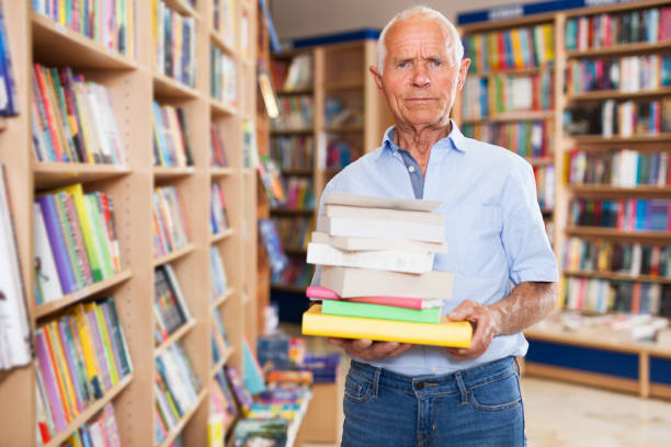 istock Elderly man holding books in bookstore 1202803210