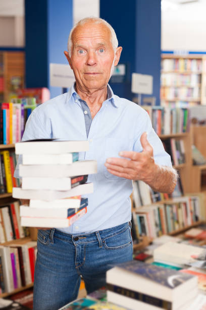 istock Elderly man holding books in bookstore 1202803219