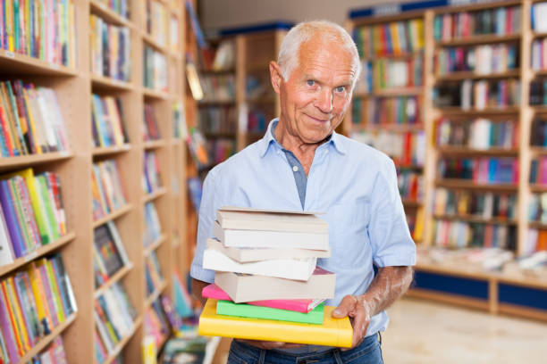 istock Elderly man holding books in bookstore 1202804388