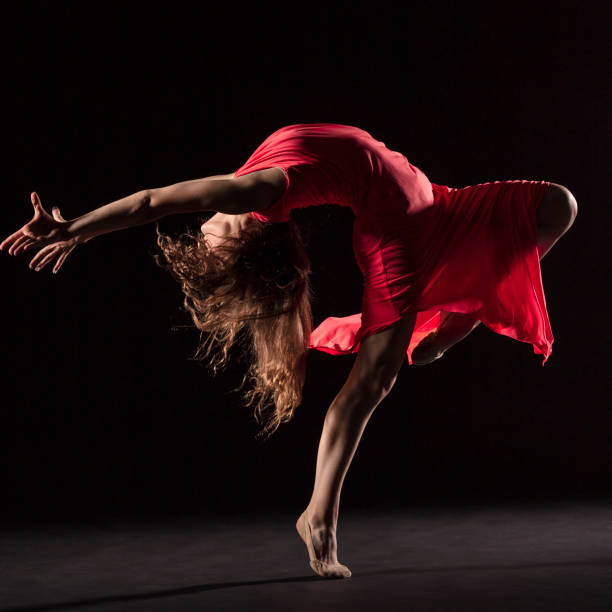 istock Dancer in red dress on black background 1202808346