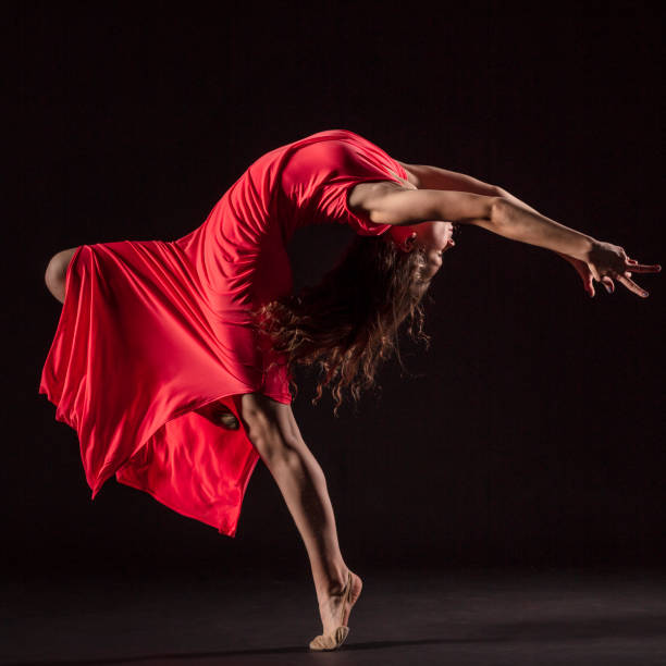 istock Dancer in red dress on black background 1202808383