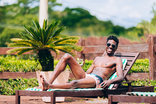 Young afro American man sunbathing at swimming pool