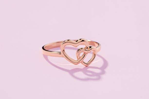 istock Hearts shape rose gold ring on pink background 1202808640