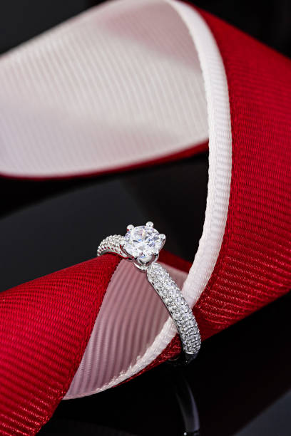 istock Wedding diamonds ring on black background with red ribbon 1202808702