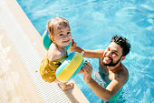 Cute little girl having fun with parents in pool