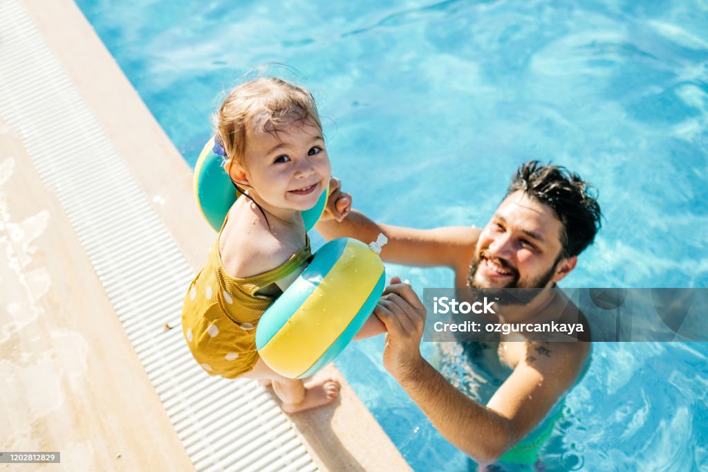 Menina fofa se divertindo com os pais na piscina - Foto de stock de Piscina royalty-free