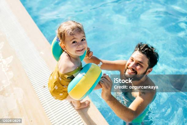 Foto de Menina Fofa Se Divertindo Com Os Pais Na Piscina e mais fotos de stock de Piscina - Piscina, Família, Criança