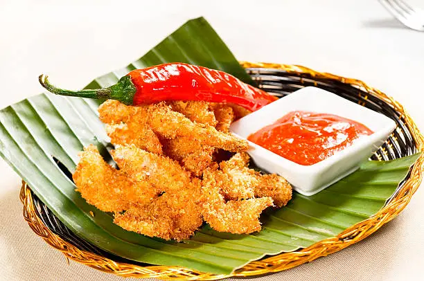 deep fried buffalo shrimps on a rattan basket with red chili pepper and ketchup on side