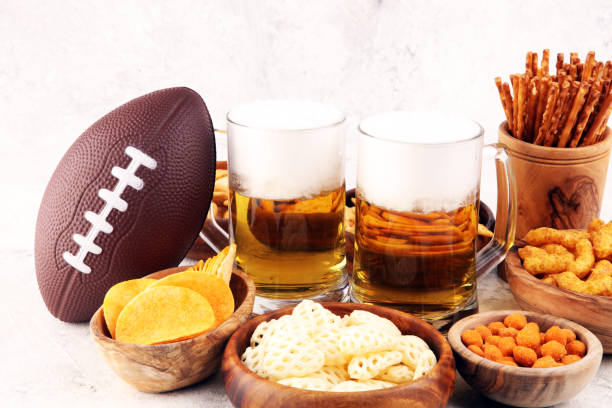 istock Chips, salty snacks, football and Beer on a table. Great for Bowl Game snack projects. 1202813018