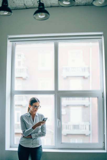 istock Young businesswoman using smart phone in modern office. 1202813231