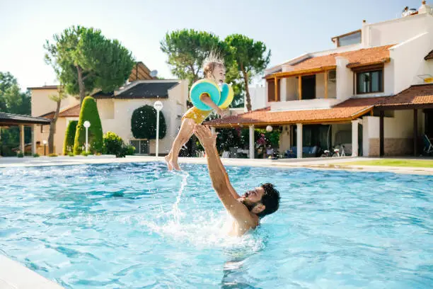 Photo of Cute little girl having fun with parents in pool