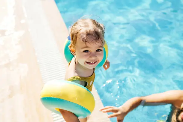 Photo of Cute little girl having fun with parents in pool