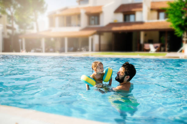 istock Cute little girl having fun with parents in pool 1202814130