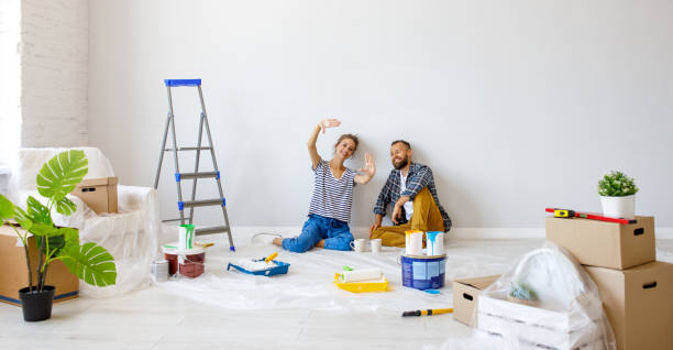 young happy family married couple dreams of renovating  house and planning  design project young happy family married couple dreams of renovating  house and planning a design project house painter ladder paint men stock pictures, royalty-free photos & images