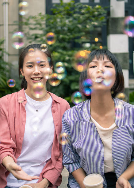 istock Young women blowing bubbles in public park 1202815475