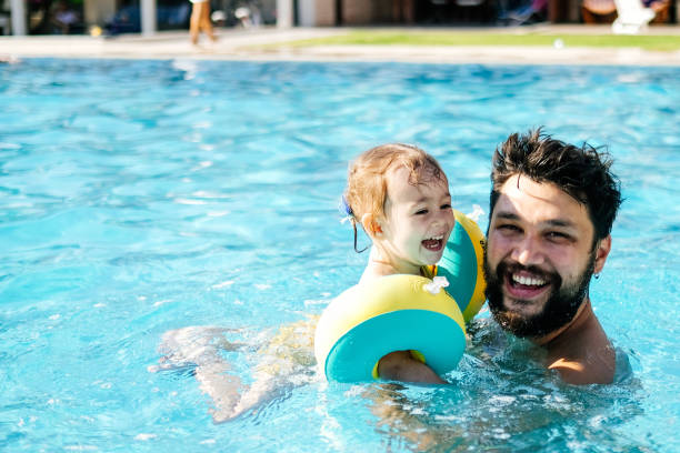 istock Cute little girl having fun with parents in pool 1202815513