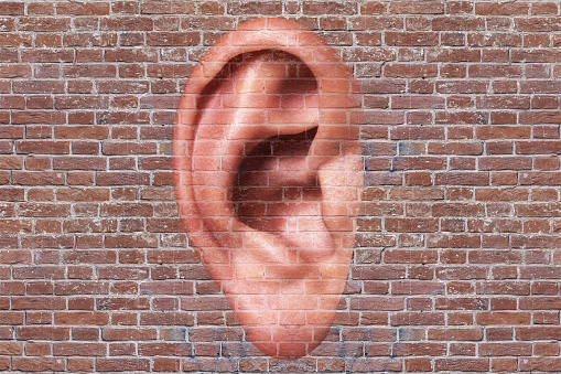 Man ear on a brick wall background. Listening concept