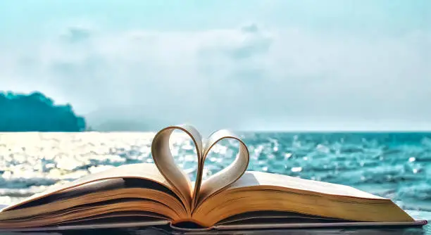 Photo of Heart shape paper book on the beach.valentine's day concept. symbol of love